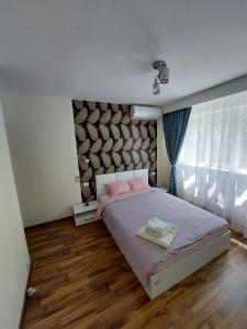 Un dormitorio con una cama con almohadas rosas. en Eugenia Apartament, en Ploieşti