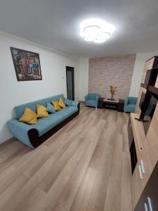 a living room with a blue couch and yellow pillows at Eugenia Apartament in Ploieşti