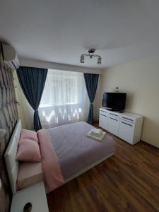 - une chambre avec un grand lit et une télévision dans l'établissement Eugenia Apartament, à Ploieşti