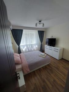 a small bedroom with a bed and a television at Eugenia Apartament in Ploieşti