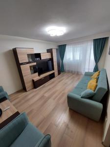 - un salon avec un canapé et une télévision dans l'établissement Eugenia Apartament, à Ploieşti