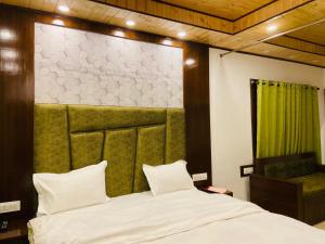 a bedroom with a white bed with a green headboard at StudioZ Paradise Hills Mussoorie in Mussoorie