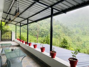 un balcone con tavolo e piante in vaso. di StudioZ Paradise Hills Mussoorie a Mussoorie