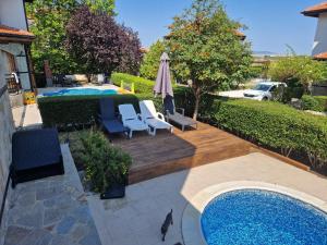 a swimming pool with two chairs and an umbrella at Victoria Villa, 13 Merlot street, The Vineyards resort, Aheloy, Pomorie. in Burgas