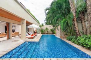 - une piscine dans l'arrière-cour d'une maison avec des palmiers dans l'établissement The Residence Villa 203, à Bang Tao Beach
