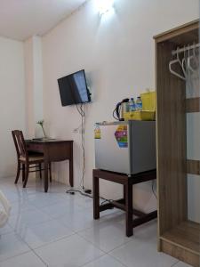 uma sala de estar com uma mesa, uma televisão e um frigorífico em V at Panus em Phanat Nikhom