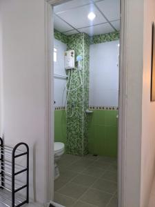 uma casa de banho com chuveiro, WC e azulejos verdes em V at Panus em Phanat Nikhom
