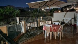 einen Tisch und Stühle mit einem Sonnenschirm auf einer Terrasse in der Unterkunft Appartamento in Complesso Sonia in Santa Teresa di Riva