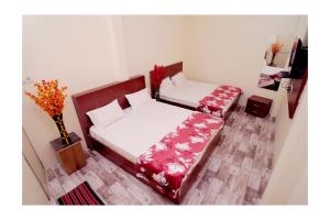 a bedroom with two beds and a vase of flowers at Rajdarshan Hotel in Ujjain