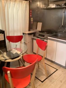 東京にあるゲストハウス羽田エアポートのキッチン(赤い椅子2脚、ガラステーブル付)