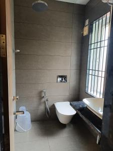 La salle de bains est pourvue de toilettes blanches et d'un lavabo. dans l'établissement SHRREYAS INN, à Kundapur