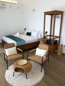 a bedroom with a bed and two chairs and a table at Villa Bari Loft in Setiu