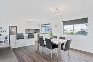 a white kitchen with a table and chairs at Ocean Pearl by Ready Set Stay - BYO LINEN & TOWELS in Surf Beach