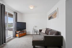 a living room with a couch and a flat screen tv at Ocean Pearl by Ready Set Stay - BYO LINEN & TOWELS in Surf Beach