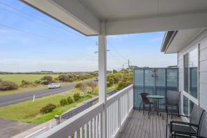 a balcony with a table and chairs and a road at Ocean Pearl by Ready Set Stay - BYO LINEN & TOWELS in Surf Beach