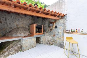 una cocina al aire libre con horno de pizza en una pared de piedra en A Casa da Rapariga de Cabelo Azul, en Manteigas