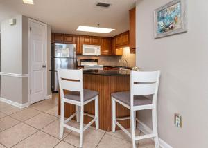 een keuken met een bar met witte stoelen bij Phoenix VII 7613 condo in Orange Beach