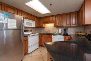 een keuken met houten kasten en een roestvrijstalen koelkast bij Phoenix VII 7613 condo in Orange Beach