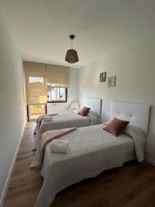 2 Betten in einem weißen Zimmer mit in der Unterkunft Apartamento Son Ría in Nigrán