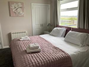 a bedroom with a large bed with two towels on it at Stoneyfield South Cottage in Stornoway