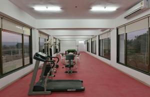 a fitness room with tread machines and windows at Ivy Zen 1 BHK with Common Pool 12 kms from Imagicaa in Jambhulpāda