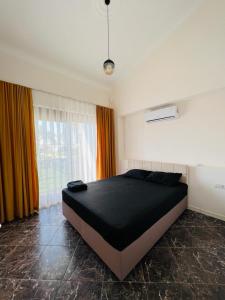 a bedroom with a large black bed in front of a window at Mandalina Apartments in Agva