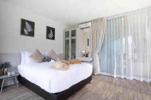 a bedroom with a large white bed and a window at Oceana Phuket in Kamala Beach