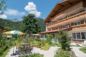 ein Hotel mit einem Innenhof mit Tischen und Sonnenschirmen in der Unterkunft Alpenhotel Dahoam in Schleching