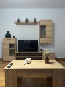 a living room with a wooden table and a tv at Apartamento Son Ría in Nigrán