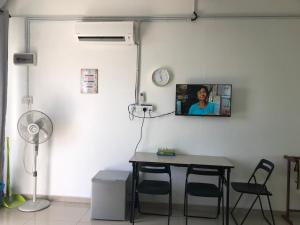Cette chambre dispose d'une table et d'une télévision murale. dans l'établissement MKB Homestay, à Shah Alam
