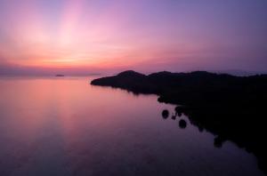 una puesta de sol sobre un cuerpo de agua con islas en ella en The Secret Karimunjawa en Karimunjawa