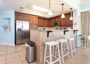 a kitchen with a stainless steel refrigerator and white stools at Phoenix Gulf Shores 1404 condo in Gulf Shores