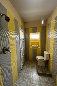 a bathroom with a toilet and yellow and gray stripes at OYO LIFE 92844 Penginapan Cibodas in Pasuruan