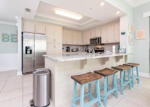 een keuken met een aanrecht met krukken en een koelkast bij Phoenix Orange Beach II 1105 condo in Orange Beach