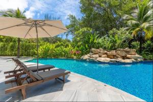 奈扬海滩2 Bedroom Apartment in Naiyang - The Title Residences, Naiyang的游泳池旁配有椅子和遮阳伞