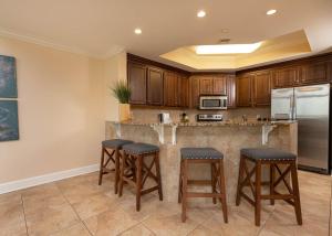 a kitchen with wooden cabinets and a large island with bar stools at The Oasis 2214 formerly Phoenix West II 2214 in Orange Beach