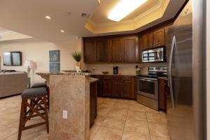 a kitchen with wooden cabinets and a stainless steel refrigerator at The Oasis 2214 formerly Phoenix West II 2214 in Orange Beach