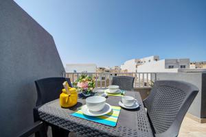 een tafel en stoelen op een balkon met uitzicht bij Few minutes from Valletta modern 2-bd roof top apartment in Marsa