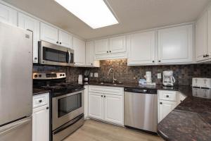 una cocina con armarios blancos y electrodomésticos de acero inoxidable en Phoenix East 410 condo, en Orange Beach