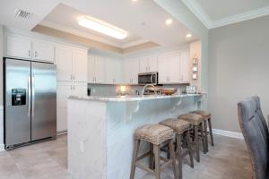 a kitchen with white cabinets and a counter with bar stools at Phoenix Orange Beach II 1104 in Orange Beach