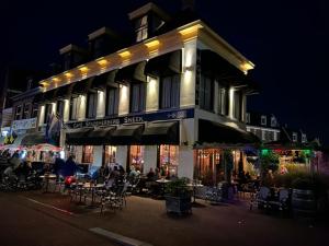 un edificio con gente sentada fuera de él por la noche en Hotel Stadsherberg Sneek, en Sneek