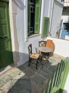 une table et des chaises à côté d'un bâtiment avec portes vertes dans l'établissement Matsas Mansions, à Folégandros