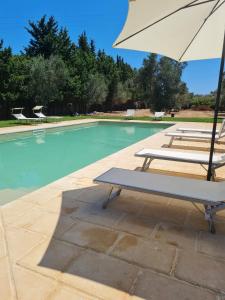 una piscina con due sedie e un ombrellone di Masseria Fagà a Otranto