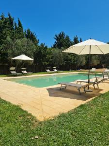 una piscina con due panche e un ombrellone di Masseria Fagà a Otranto