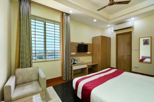范兰德凡Hotel SKS Grand Palace-Vrindāvan的一间卧室，里面有一张床、一把椅子和一扇窗户 更多37张照片