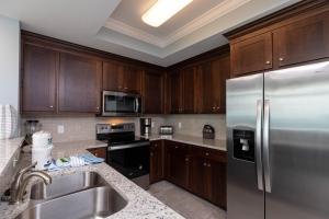 a kitchen with wooden cabinets and a stainless steel refrigerator at Phoenix Orange Beach II 1103 condo in Orange Beach