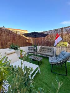 un patio con 2 sofás y una sombrilla en Monaco Cap d’ail Studio & jardin, en Cap d'Ail