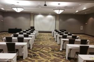 SpringHill Suites by Marriott Denton في دينتون: قاعة اجتماعات بطاولات بيضاء وكراسي وشاشة