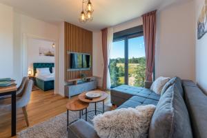 uma sala de estar com um sofá azul e um quarto em Zlatibor Pine View em Zlatibor