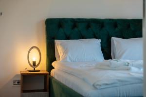 uma cama com uma cabeceira verde e um candeeiro sobre uma mesa em Zlatibor Pine View em Zlatibor